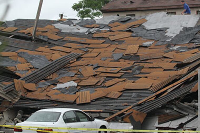 Frank Lubinsky Jr, of Union Roofing is on the collapse roof of R & R Car Repair at 9909 Northeast Ave., where a tornado was suppose to have touched down. One person was under it when it collapsed but was unharmed and crawled out right after the collapse. (Michael Bryant / Staff Photographer)