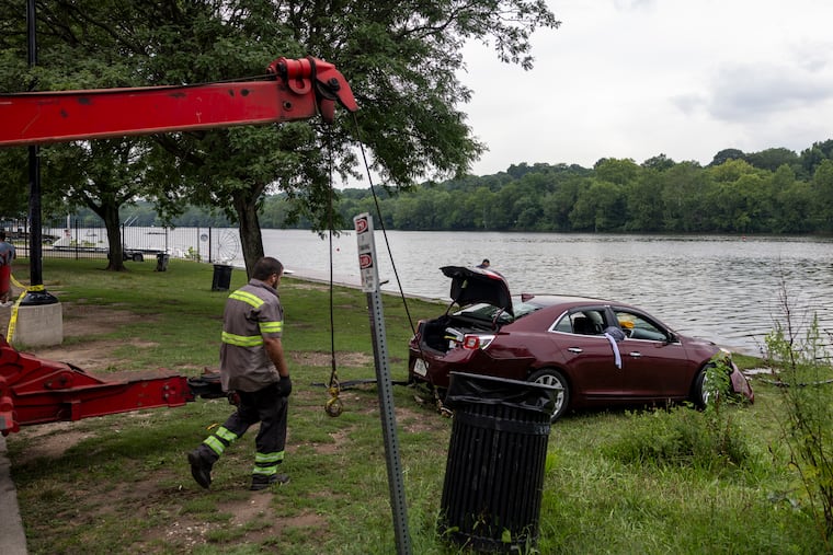 A tow truck pulling out and loading up a car after it had plunged into the Schuylkill and the driver was helped by bystanders to escape.