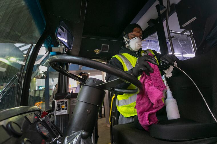 Ryan Stewart wipes down a SEPTA bus at the Olney Transportation Center. He takes pride in his work and in his designation as an essential worker. But if he's that essential, why can't he get a free coronavirus test at Rite Aid, or a free coffee at Wawa, where signs thanking essential workers cover the glass windows?