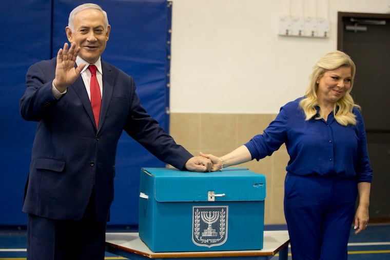 Israeli Prime Minister Benjamin Netanyahu, left, waves with his wife Sara after voting during Israel's parliamentary elections in Jerusalem, Tuesday, April 9, 2019.