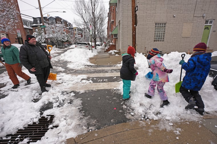 Leanne Deacon, left, and Andrew Fox, second from left, look on as Stella, Liliana and Charlie Phoenix play in the snow on Monday.