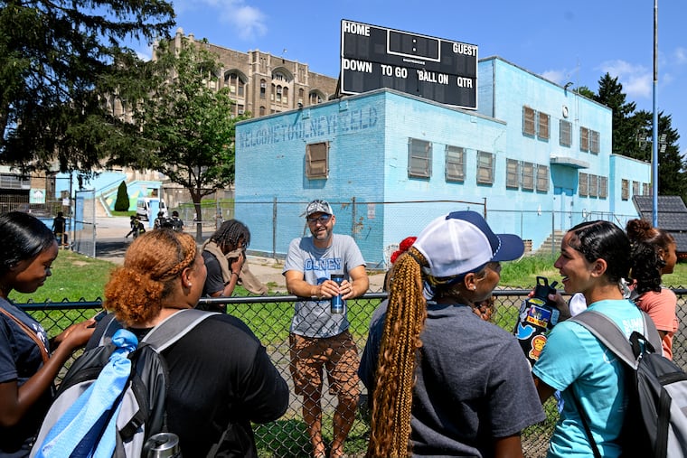 Olney High School principal Michael Roth talks with student-athletes following a lacrosse summer camp practice in July. The school’s sports facilities are in deplorable condition, including the fieldhouse (rear), which has been condemned, so there's no place for athletes to change, no access to running water or bathrooms, and no place to store equipment.