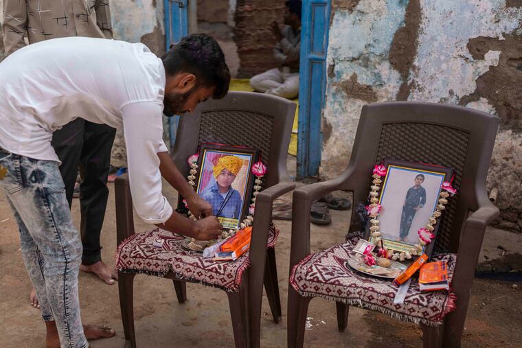 A relative puts incense sticks by the photograph of Yash Devadana (left), 12, and his cousin Raj Baghwanji Bhai, 13, who died in Sunday's bridge collapse.