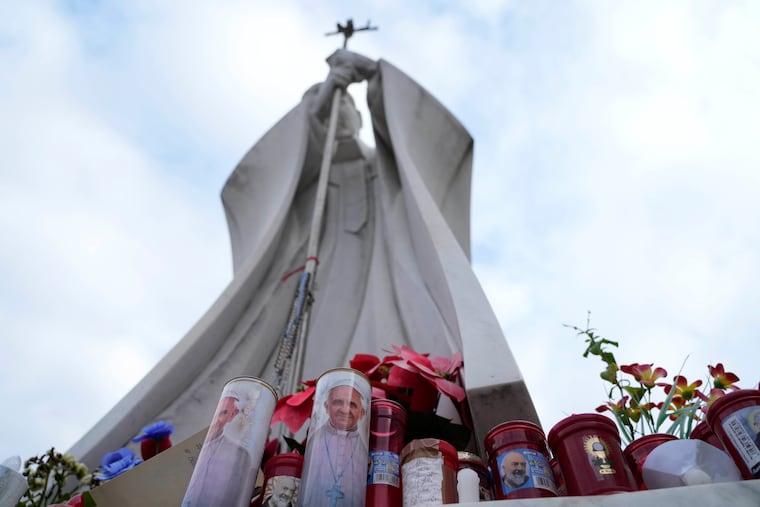 Candles with pictures of Pope Francis are laid under the statue of late Pope John Paul II outside Agostino Gemelli Polyclinic in Rome on Wednesday, Feb. 19, 2025, where the Pontiff has been hospitalized since Friday, Feb. 14.