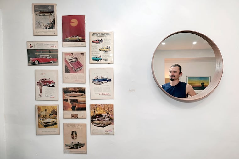 Dylan Foglesong is reflected in a mirror that hangs, next to classic car ads, in the foyer of his home.