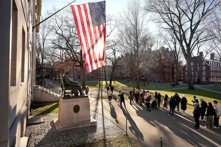 FILE - People take photos near a John Harvard statue, left, on the Harvard University campus, Jan. 2, 2024, in Cambridge, Mass. r. (AP Photo/Steven Senne, File)