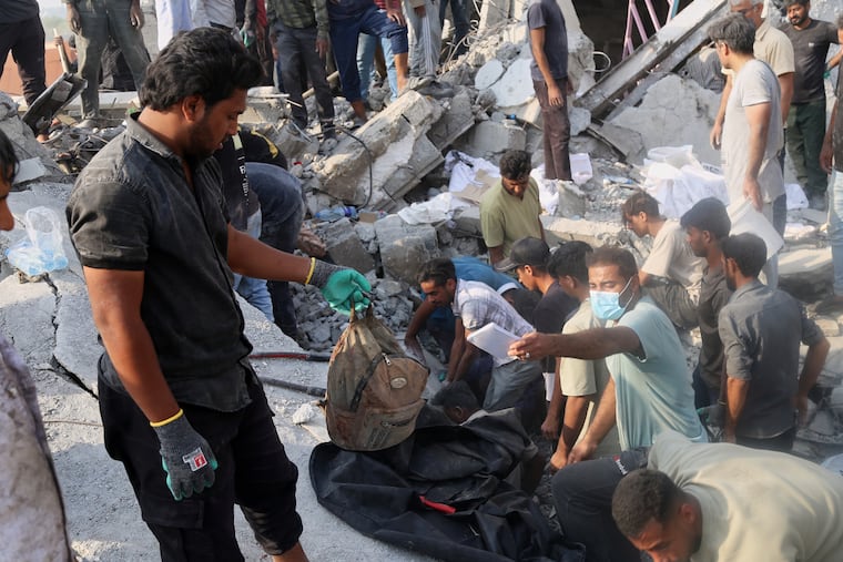 A man hold a child's backpack as rescue workers and residents search through the rubble in the aftermath of an Israeli-U.S. strike on a girls' elementary school in Minab, Iran, on Feb. 28.