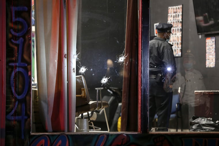 Police look over the scene of a Barbershop at 5104 Germantown Avenue where two people were shot in their barber chairs through the front window waiting for a haircut, Tuesday, November 17, 2020