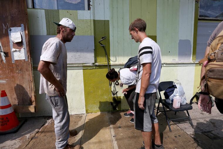 A group gathers to use a hose for water outside the Last Stop outpost on Somerset Street in Philadelphia.