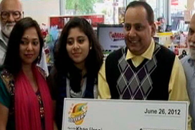 Urooj Khan holds a ceremonial check at a lottery office in Chicago. His wife, Shabana Ansari (left), was among those who accompanied him.