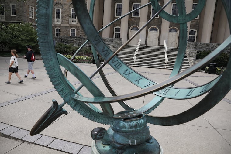 Two people walk past Old Main on the largely deserted Penn State University campus in State College, Pa., on Tuesday, June 23, 2020. The campus is emptier than usual because the university canceled its in-person summer classes and new student orientation sessions in response to the coronavirus pandemic.
