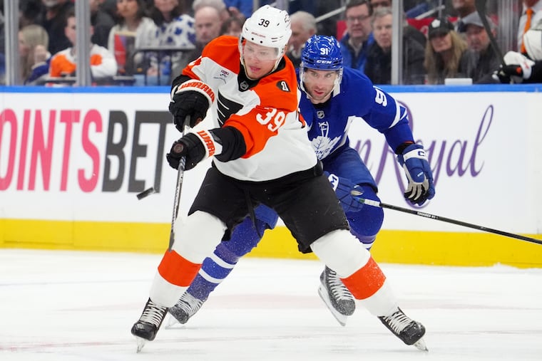 Matvei Michkov passes the puck while under pressure from the Toronto Maple Leafs' John Tavares.