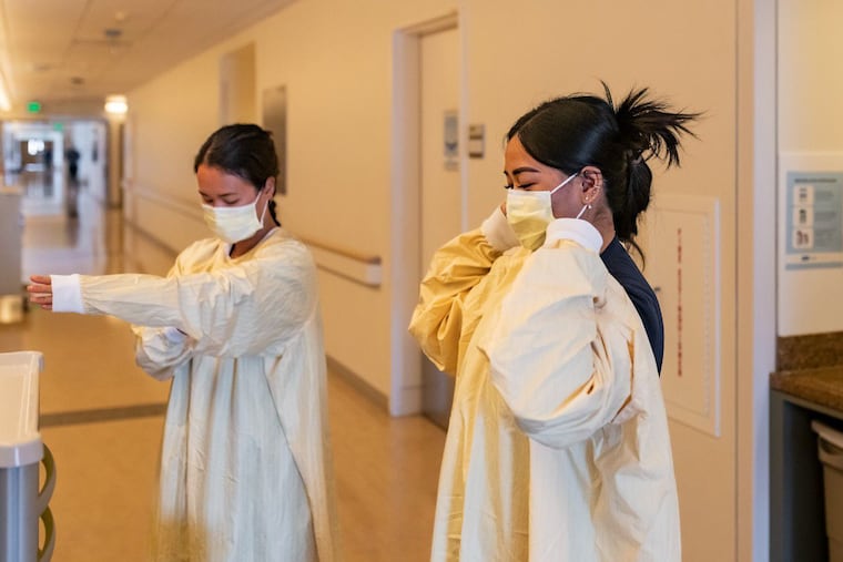 Nurses Catherine Luu (left) and Cathleen Martinez don reusable isolation gowns at Ronald Reagan UCLA Medical Center in Los Angeles.