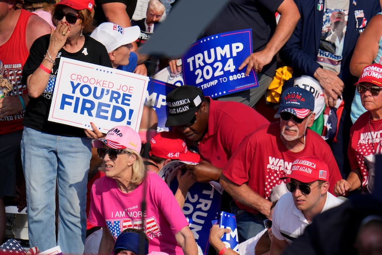 Members of the crowd react as U.S. Secret Service agents surround Republican presidential candidate former President Donald Trump at a campaign event in Butler, Pa., Saturday after shots were fired.