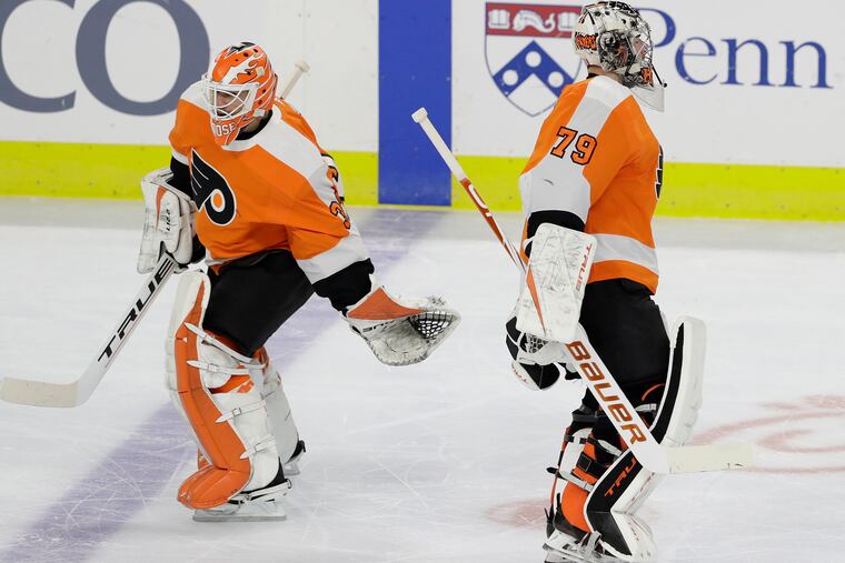 Flyers goaltender Carter Hart skates past teammate Brian Elliott after Hart was replaced in the second period against the Buffalo Sabres on Jan. 18. Elliott also replaced Hart against the Sabres on Tuesday.