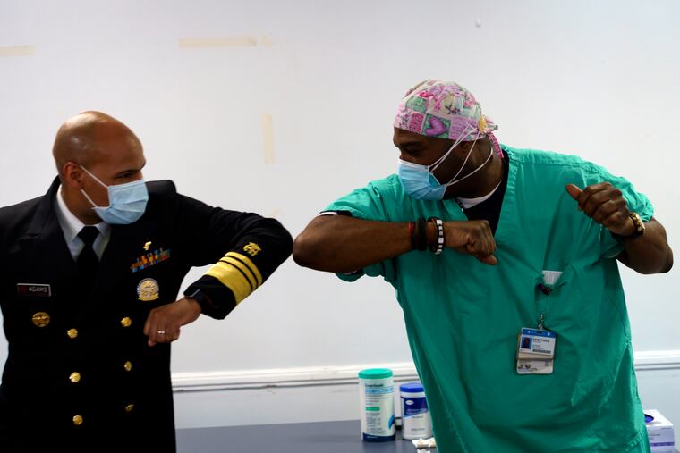 Surgeon General of the U.S. Jerome Adams, left, elbow-bumps Emergency Room technician Demetrius Mcalister after Mcalister got the Pfizer COVID-19 vaccination at Saint Anthony Hospital in Chicago, on Tuesday, Dec. 22, 2020.