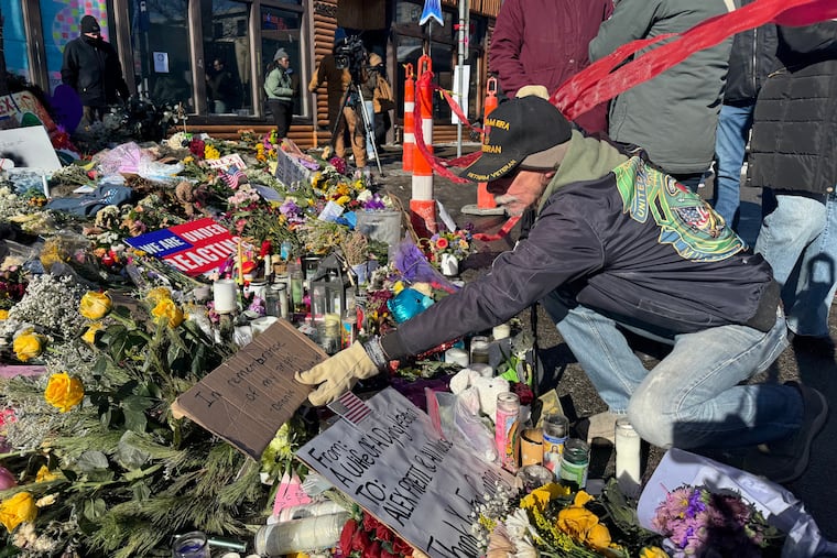 Vietnam War veteran Donnie McMillan places a sign Wednesday that says "In remembrance of my angel" at a memorial set up at the location where Veterans Affairs nurse Alex Pretti was shot by federal agents in Minneapolis.