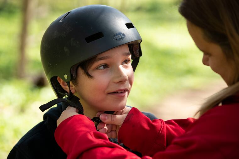 Karen Nudy Pecora adjusts the helmet on her son Dominick Pecora, 11, in the woods near their home.