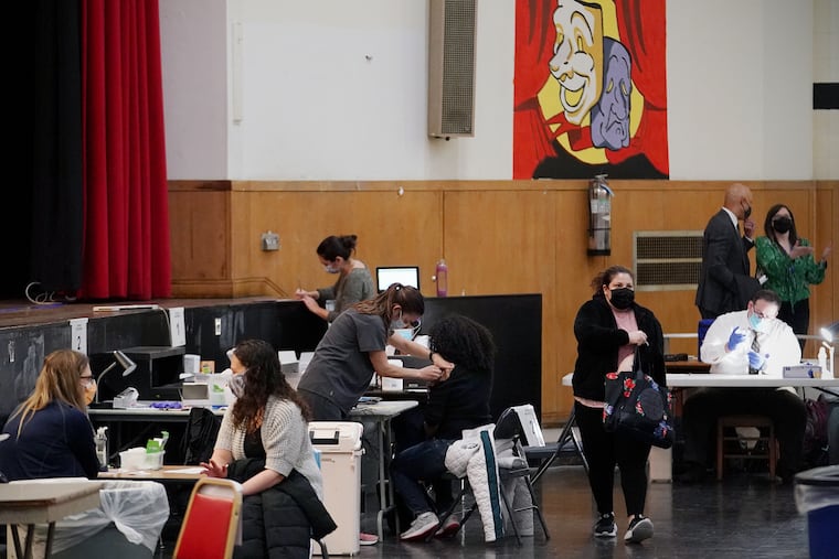 A health-care worker administers a COVID-19 vaccine at South Philadelphia High School in this March file photo. The school system has a vaccine mandate and about 80% of workers are fully vaccinated.