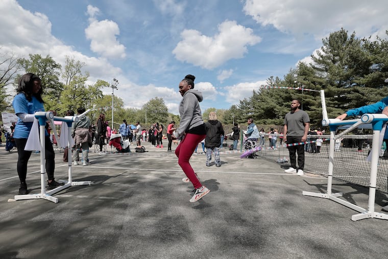 Dr. Tahira Reid Smith (left) the Smithsonian-featured inventor and Penn State engineering professor who first sketched an automated double Dutch machine as an 8-year-old in the Bronx, demonstrates her working prototype to Sarina Hudson (center) of Philly at the Philly Girls Jump event at Awbury Park in Philadelphia on Saturday, May 2, 2026.