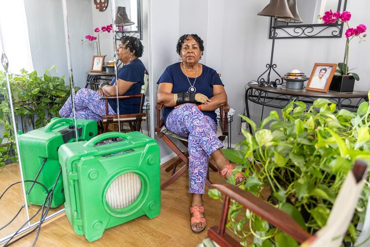 Gloria L. Pemberton, 77, of West Philadelphia, Pa., poses for a portrait with one of the two giant air purifiers she temporarily got after another fire broke out at the junkyard around the corner of her home in West Philadelphia.
