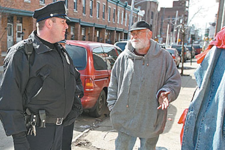 Officer Brian McBride talks in Frankford with Chris O’Leary, whose neighborhood was the worst for crime, according to a Temple University study that shows foot patrols helped. (MICHAEL BRYANT / Staff Photographer)