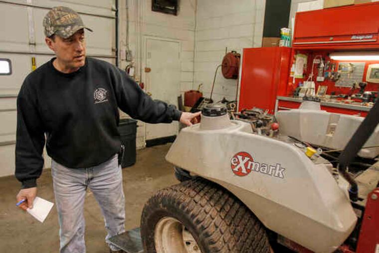 Robert Jones of R.J. Power Equipment checks over a broken commercial lawn mower than needs to be repaired. Before the recession, the owner would likely have bought a new one.