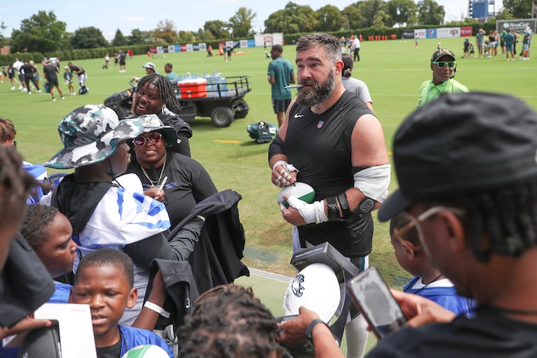 Eagles center Jason Kelce signing footballs and other items for youngsters at the end of a training camp session at the NovaCare Complex on Saturday.