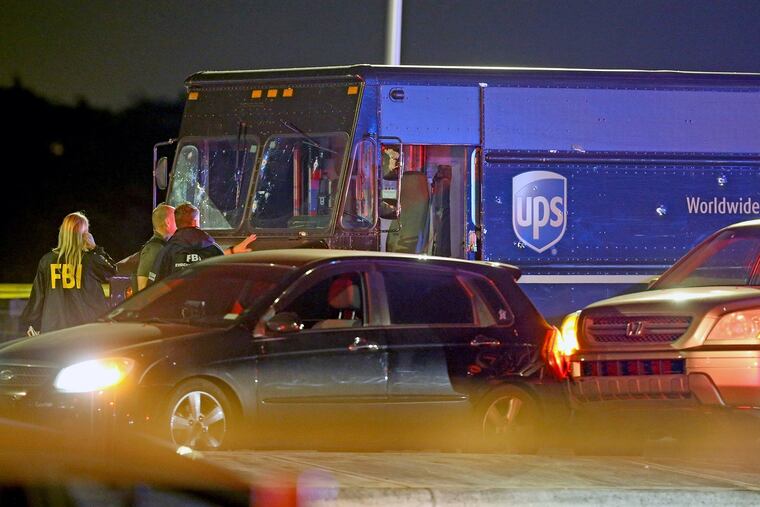 Law enforcement stand near a vehicle that appears to be part of the crime scene where four people were killed, Thursday, Dec. 5, 2019 in Miramar, Fla. The FBI says four people, including a UPS driver, were killed after robbers stole the driver's truck and led police on a chase that ended in gunfire at a busy Florida intersection during rush hour.