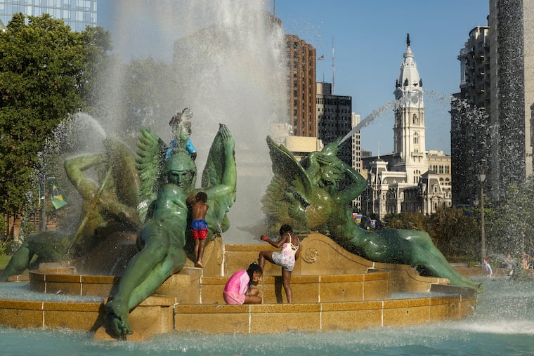 Children climb the statues at Logan Square on a warm day in June.