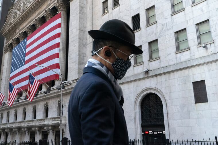A man wearing a mask passes the New York Stock Exchange. Stock markets are rallying on news that a second coronavirus vaccine shows promise.