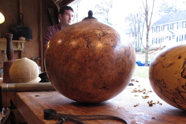 Two finished funerary urns, far left, by woodturner Jason Van Duyn sit in his Raleigh, N.C., studio. He is competing in a national urn show next month.