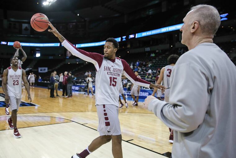 With assistant coach Dave Duda watching and teammate Markell Lodge in the background, Saint Joseph's forward Isaiah Miles throws a pass during practice.