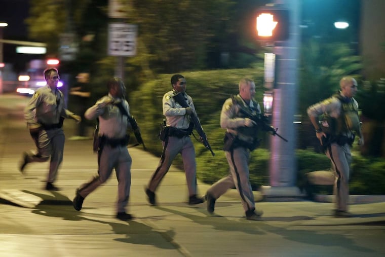 Police run to cover at the scene of a shooting near the Mandalay Bay resort and casino on the Las Vegas Strip, Sunday, Oct. 1, 2017, in Las Vegas. Multiple victims were being transported to hospitals after a shooting late Sunday at a music festival on the Las Vegas Strip.