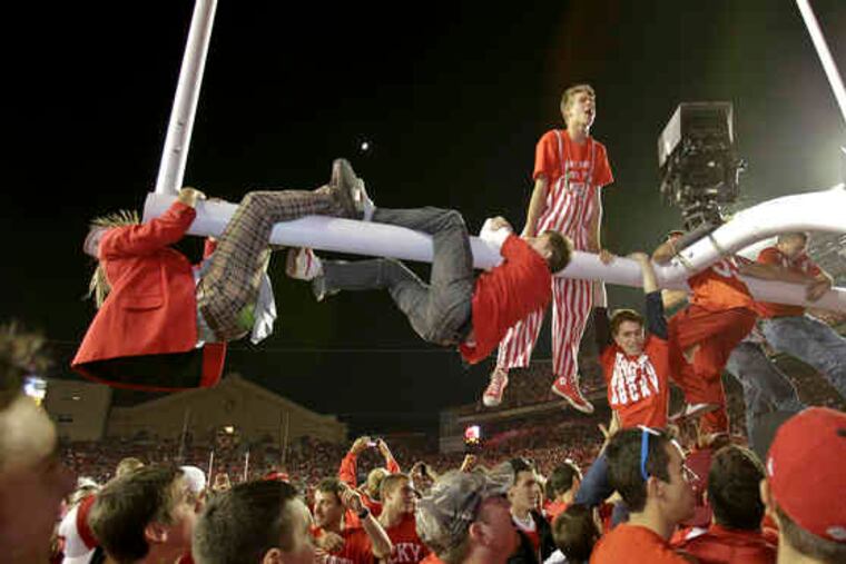 Wisconsin fans climb the goalposts in celebration after the 18th-ranked Badgers upset visiting Ohio State, 31-18. For the second week in a row there will be a new No. 1 team.
