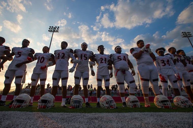 Imhotep players stand arm-in-arm before their game against. La Salle High School at Upper Dublin High School on Aug. 24, 2018. CHARLES FOX / Staff Photographer