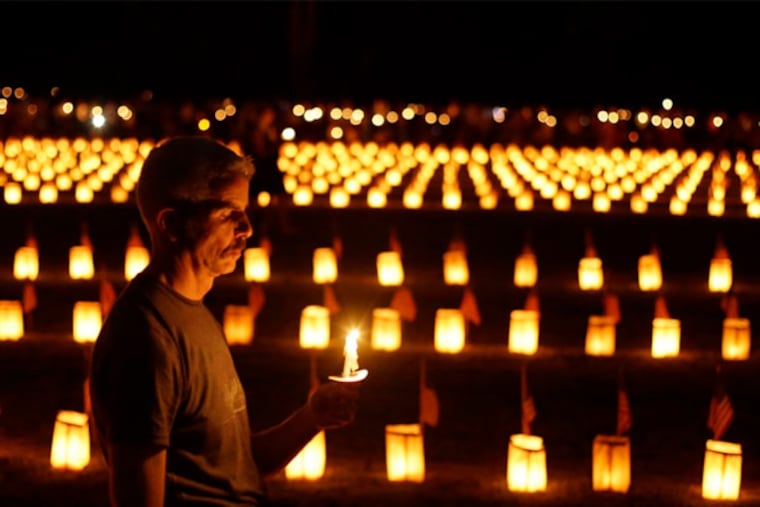 A member of the public holds a candle near luminaries that mark the graves of Union dead at Soldiers' National Cemetery during ongoing activities marking the 150th anniversary of the Battle of Gettysburg, Sunday, June 30, 2013, in Gettysburg, Pa. (AP Photo/Matt Rourke)