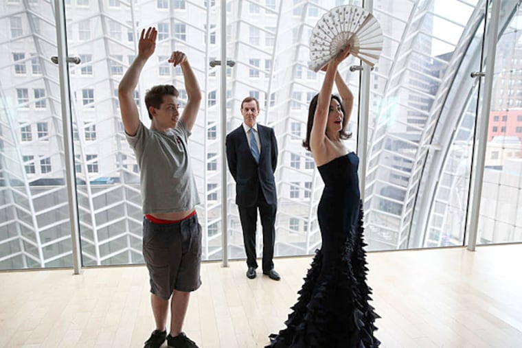 Catherine Clifton receives dance tips from David Rubio (left), a student at the High School for Creative and Performing Arts as her husband, Anthony, watches on the garden roof at the Kimmel Center. The Cliftons created an award for young artists; Rubio is a recipient. (David Maialetti / Staff Photographer)