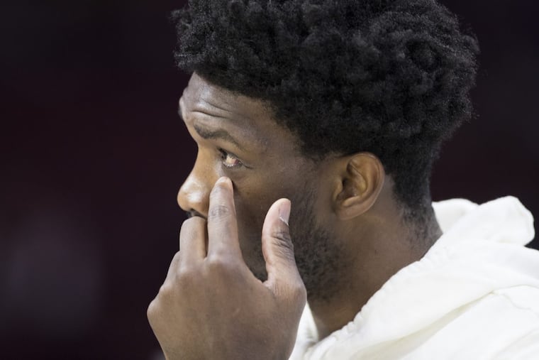 Joel Embiid of the Sixers on the sidelines before their game against the Cavaliers at the Wells Fargo Center on April 6, 2018. Embiid reaches up to the eye area where he recently had surgery for a fractured orbital.