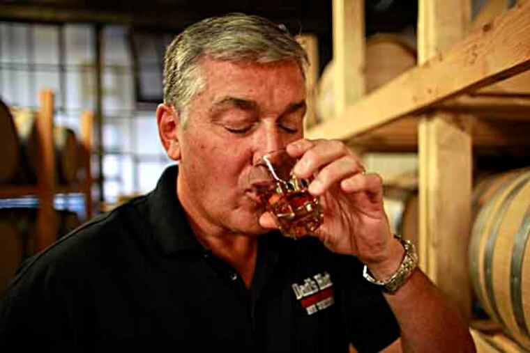 After uncorking a barrel and using a "thief" to gather a sample, John Cooper tastes his aging Pennsylvania rye whiskey called Dad's Hat in the Bristol, Pa., distillery August 5, 2013. ( DAVID SWANSON / Staff Photographer )