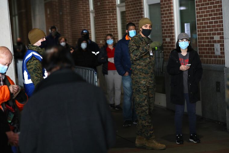People wait in a long but brisk line as they arrive on the first day of the FEMA COVID-19 vaccination site at the Pennsylvania Convention Center in Center City Philadelphia on Wednesday, March 3, 2021.