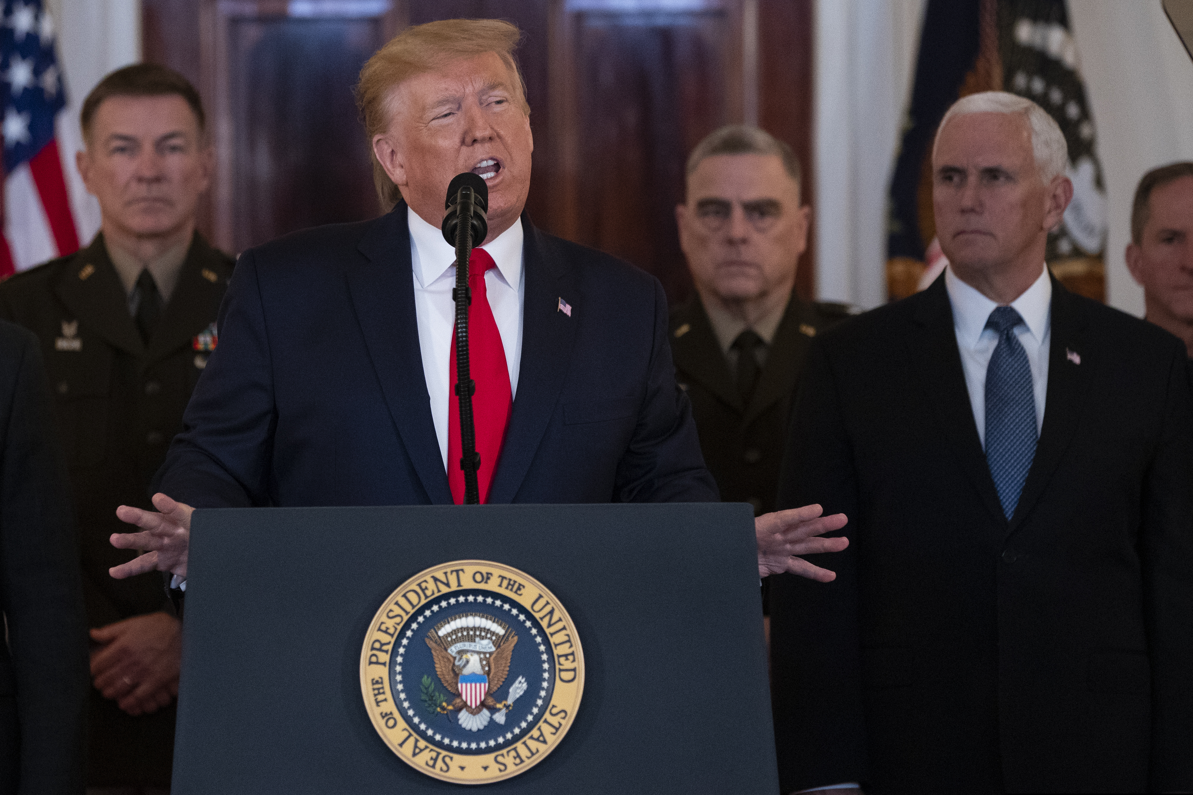 President Donald Trump addresses the nation from the White House on the ballistic missile strike that Iran launched against Iraqi air bases housing U.S. troops, Wednesday, Jan. 8, 2020, in Washington, as Chairman of the Joint Chiefs of Staff Gen. Mark Milley, Vice President Mike Pence, and others look on.