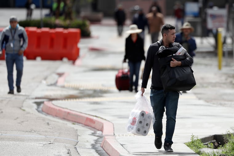 A man carries toilet paper after crossing the border from Tijuana, Mexico, to San Diego.