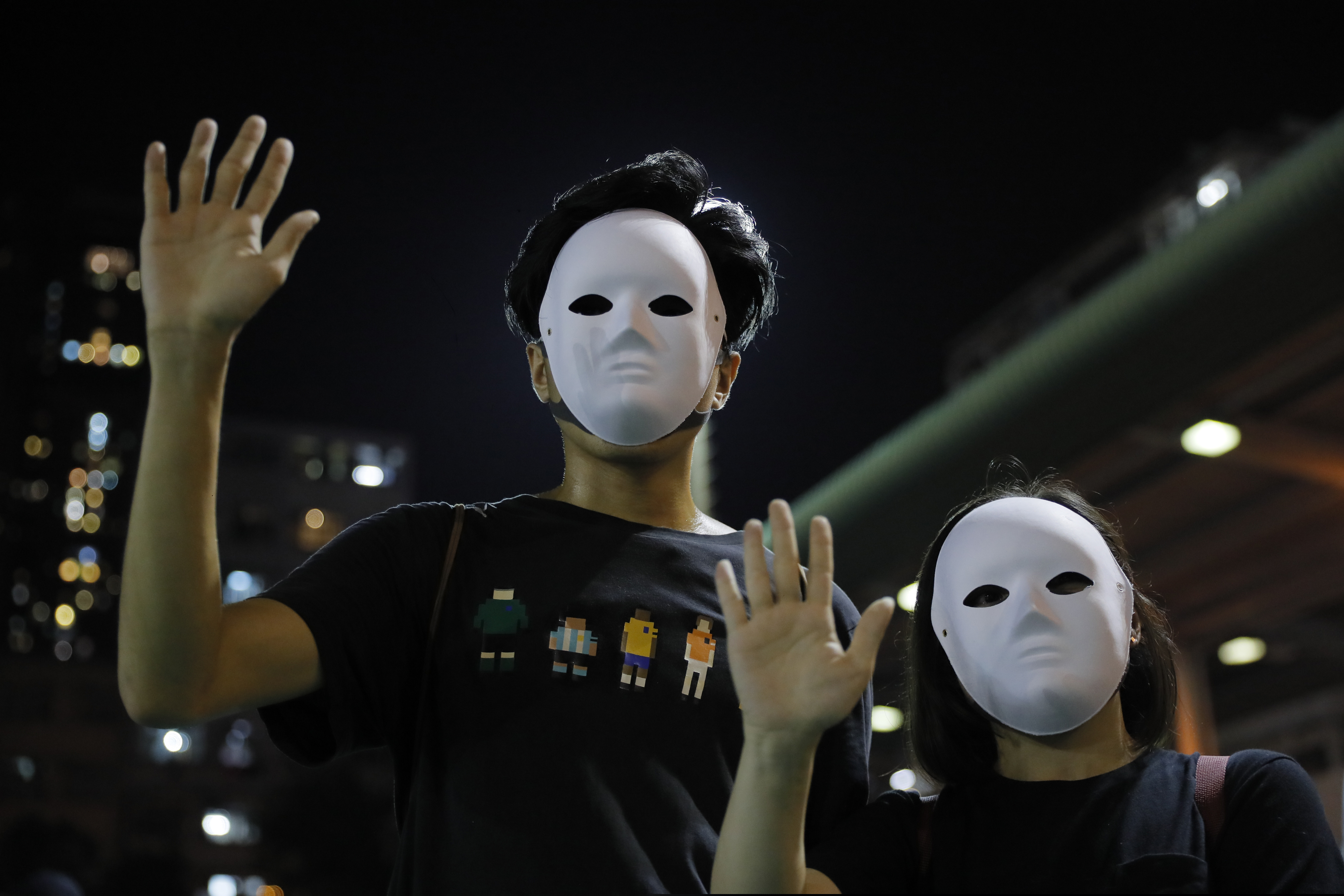 Masked protesters hold up their hands to represent their five demands in Hong Kong on Saturday, Oct. 5, 2019.