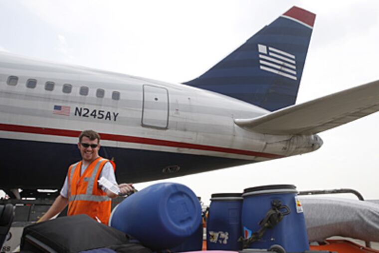 Chris Reynolds, a U.S. Airways fleet service agent at Philadelphia International Airport, unloads luggage from a Milan flight. (Michael S. Wirtz / Inquirer).
