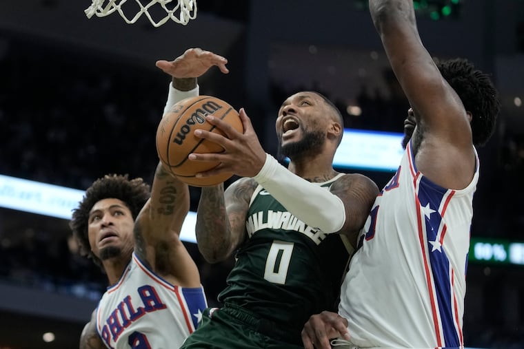 Damian Lillard shoots between Kelly Oubre Jr. (left) and Joel Embiid during the second half.