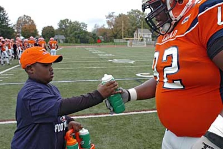 Xavier Oliver gives big defensive lineman Shawn Hart, 6' 1", 315 lbs, a bottle of water. ( Clem Murray / Staff Photographer )