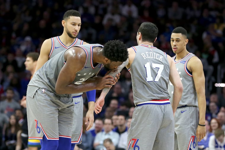 Joel Embiid (second from left) kisses the elbow of teammate JJ Redick after Redick suffered a hard fall against the Bucks on Thursday.