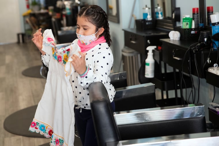 Keily Tendencias, 9, holds up a piece of the traditional embroidery she wears when attending the Lady of Guadalupe procession and Mass, She is inside her mother’s salon in South Philadelphia on Thursday, Dec. 10, 2020.