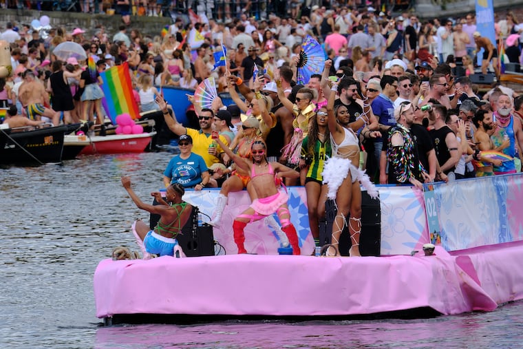 People celebrate atop a boat on one of the Dutch capital's historic canals, Saturday, Aug. 1, 2026, during the Canal Parade, the most popular event of the Pride Amsterdam festival.